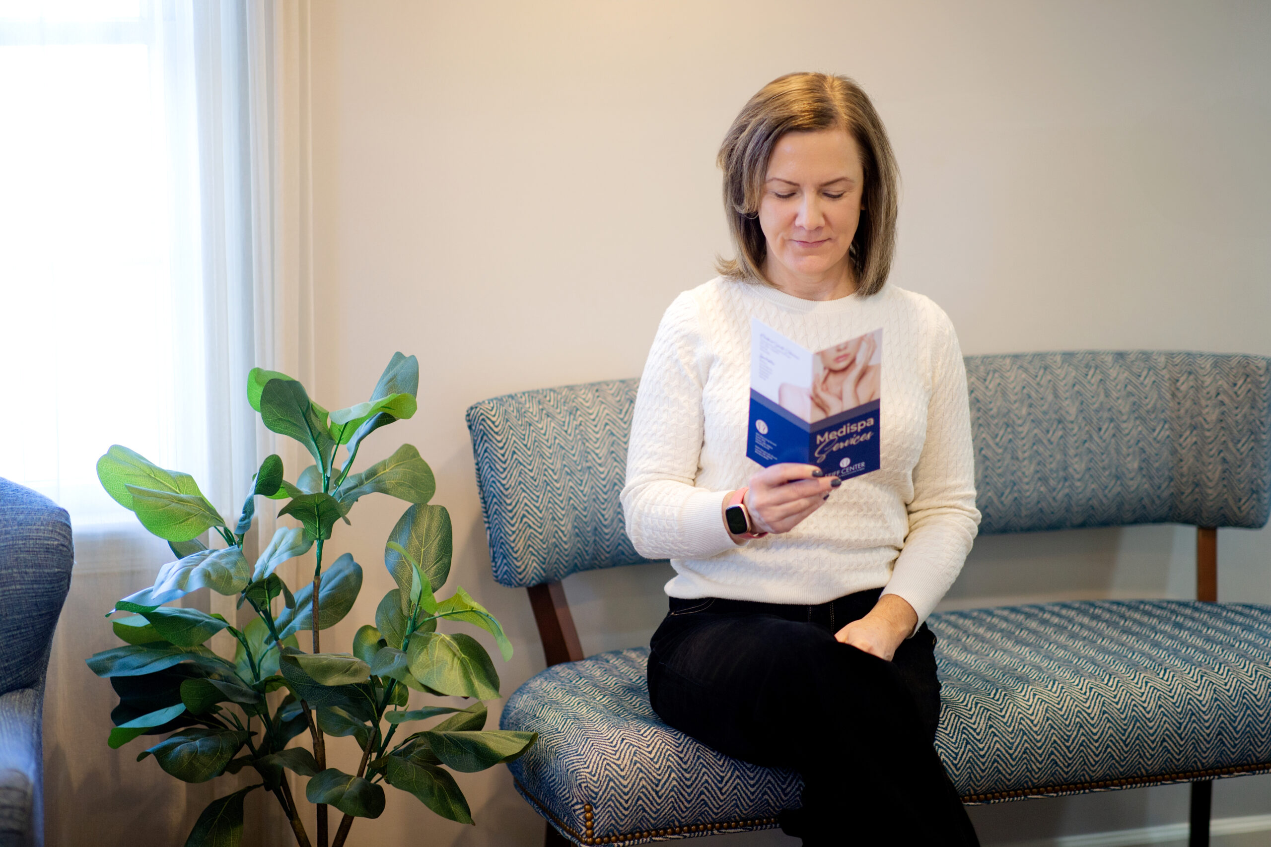 a woman sitting in Seiff Center Lobby waiting her hair treatment appointment
