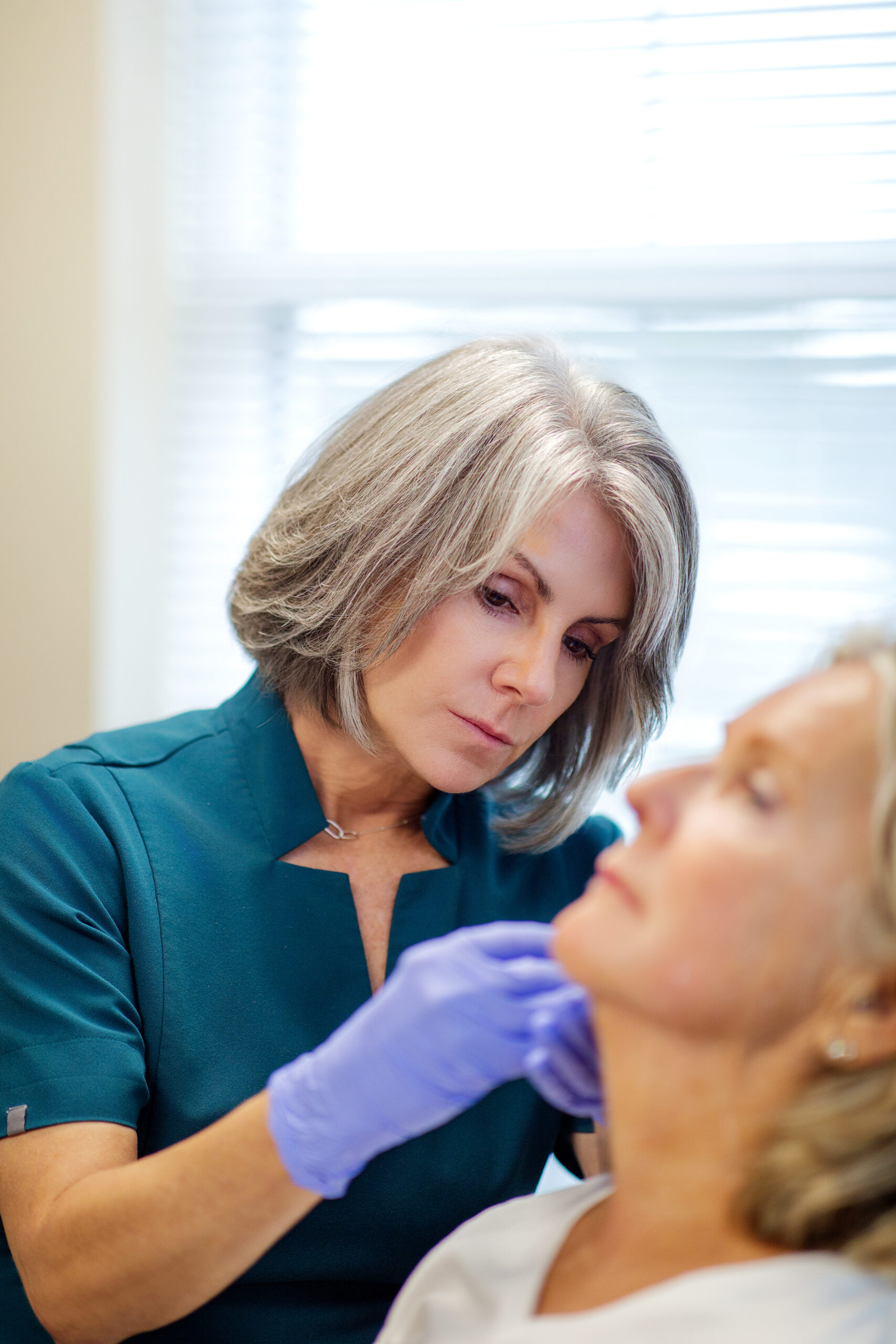 a woman Cosmetic Injector looking at a woman's face