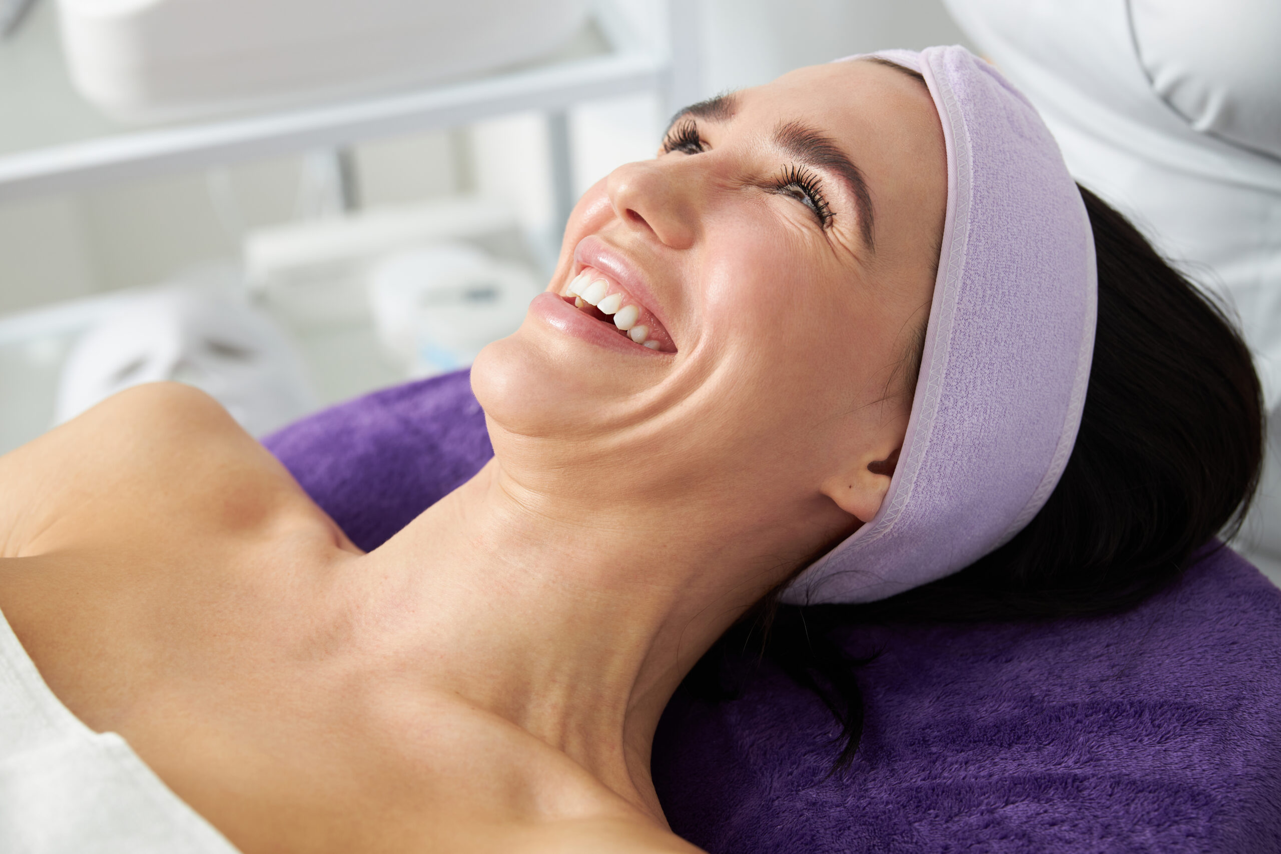 a woman with a towel on her head smiling in a cosmetology cabinet